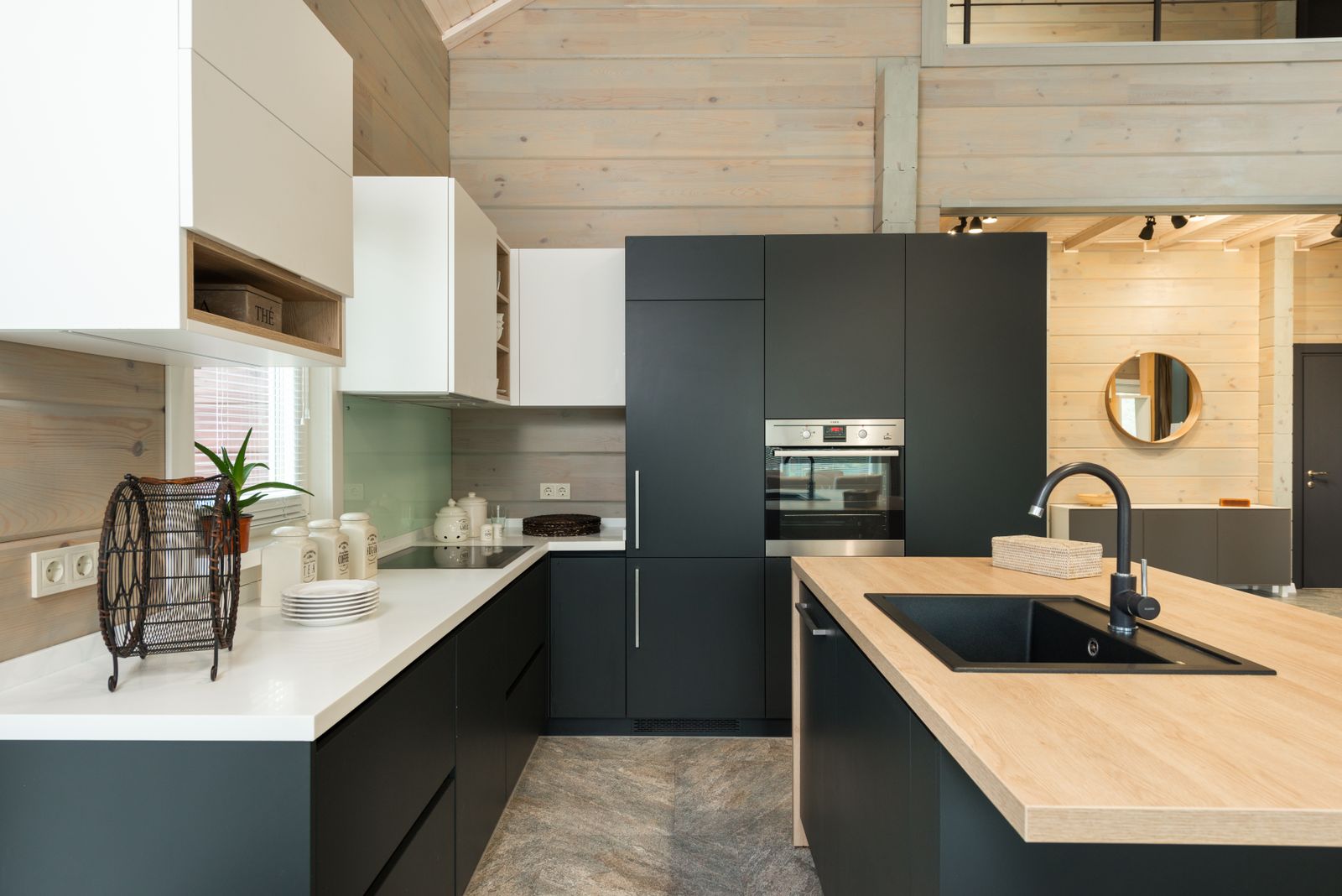 Interior of stylish kitchen with minimalist black and white cabinets built in oven and stove with sink in counter